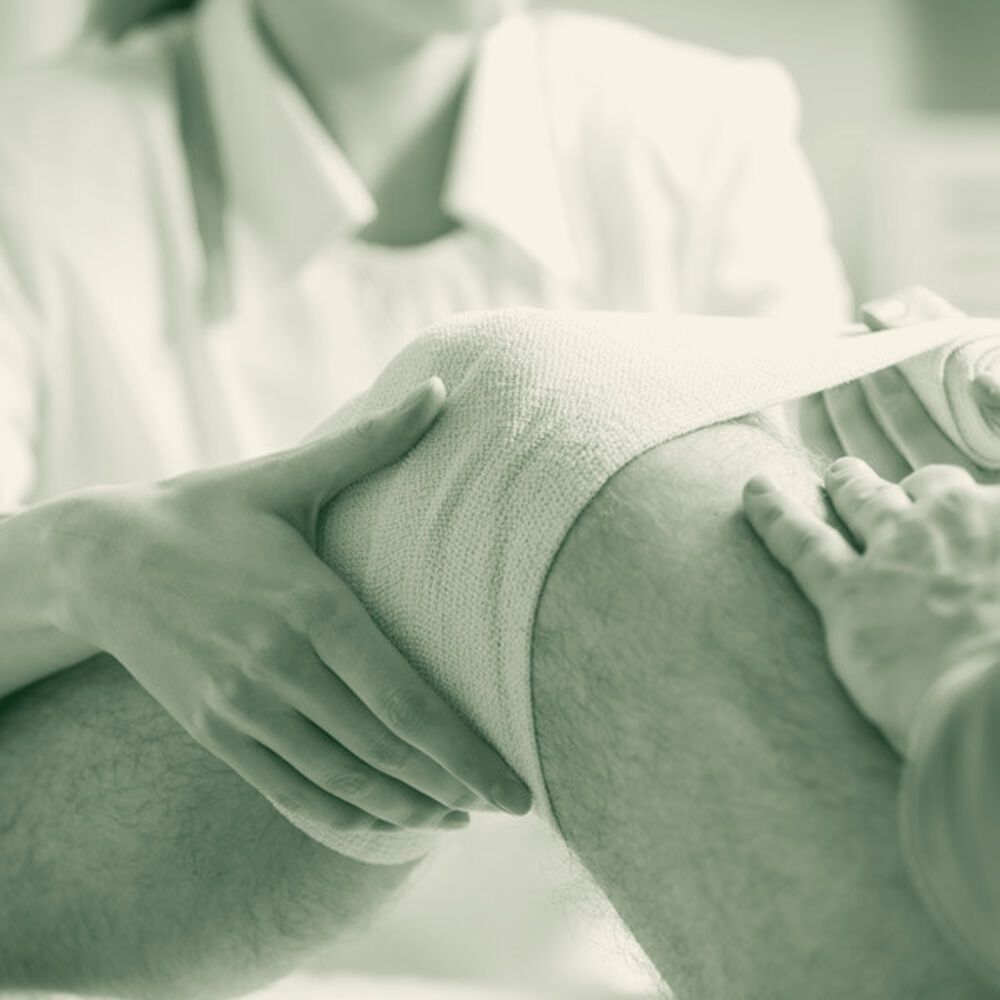A clinician wrapping a bandaged knee during routine wound care
