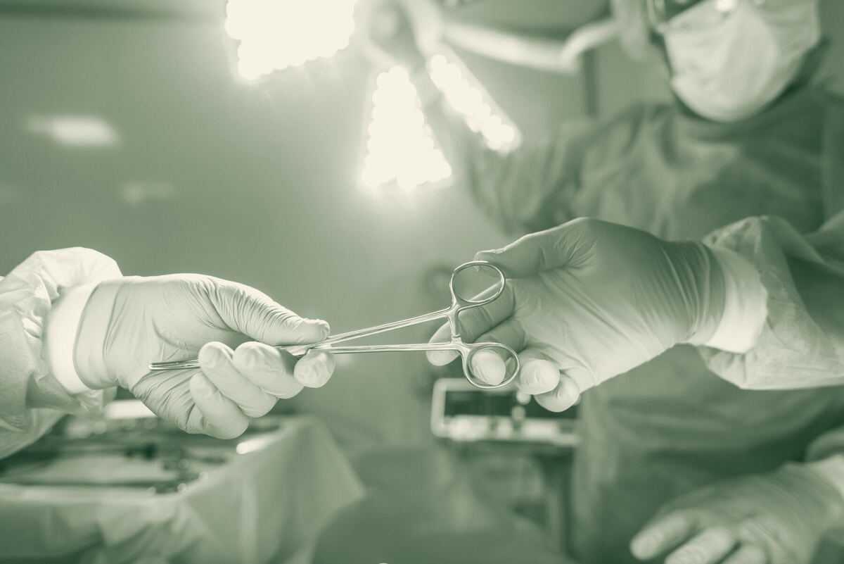 Gloved hands passing sterile instruments